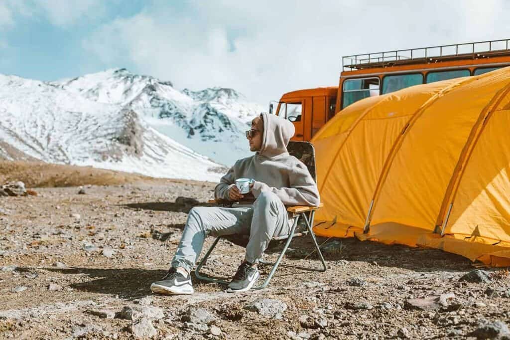 a guy camping at the top of a snowy mountain