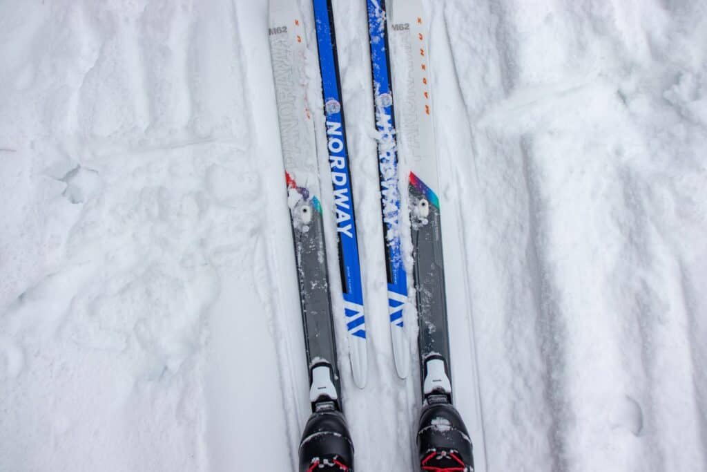 A Person Wearing Snow Skis on Snow Covered Ground where you could see the ski waist width