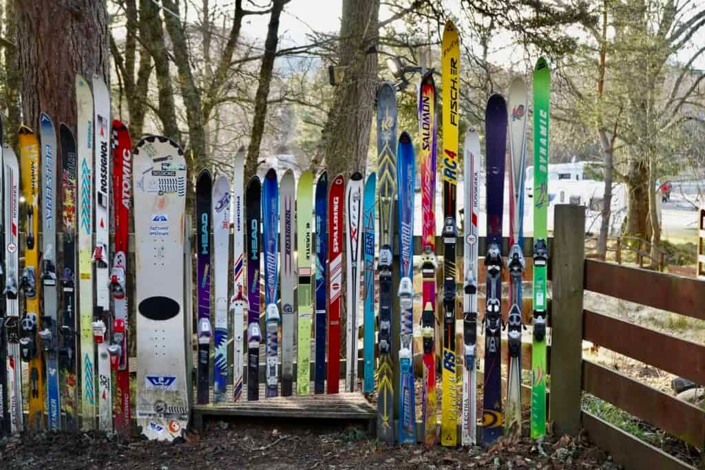 Ice Skis and Snowboard Leaning on Wooden Fence