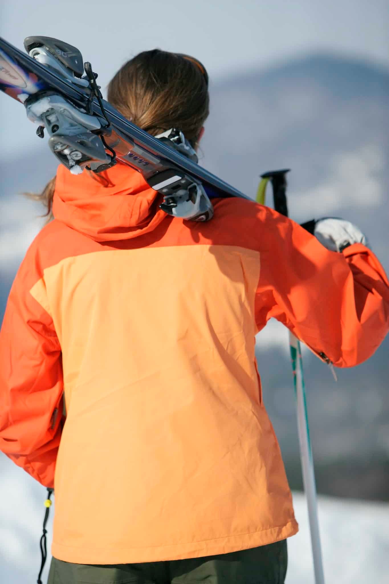 Person in Orange Jacket Carrying Ski and Ski Pole wearing a ski jacket