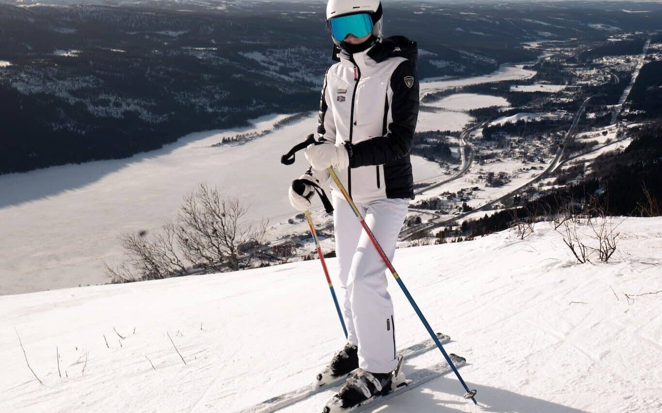 Person in White Jacket and White Ski bib Riding Ski Blades on Snow Covered Mountain