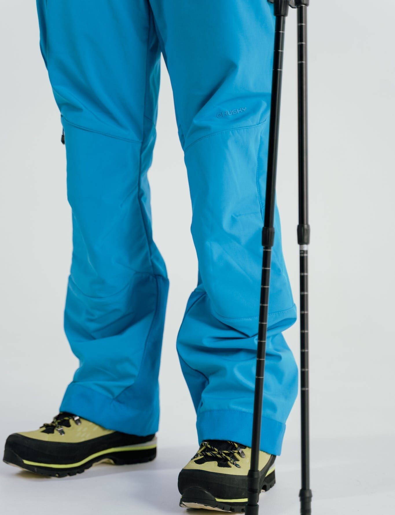 Person Standing in Blue Ski Pants Beside Ski Poles