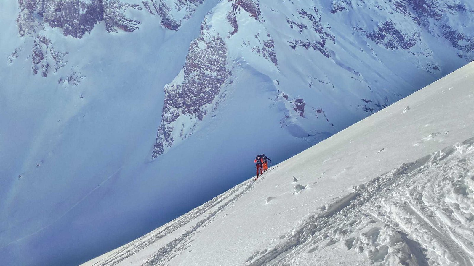 Faceless skiers riding towards snowy rough mountain