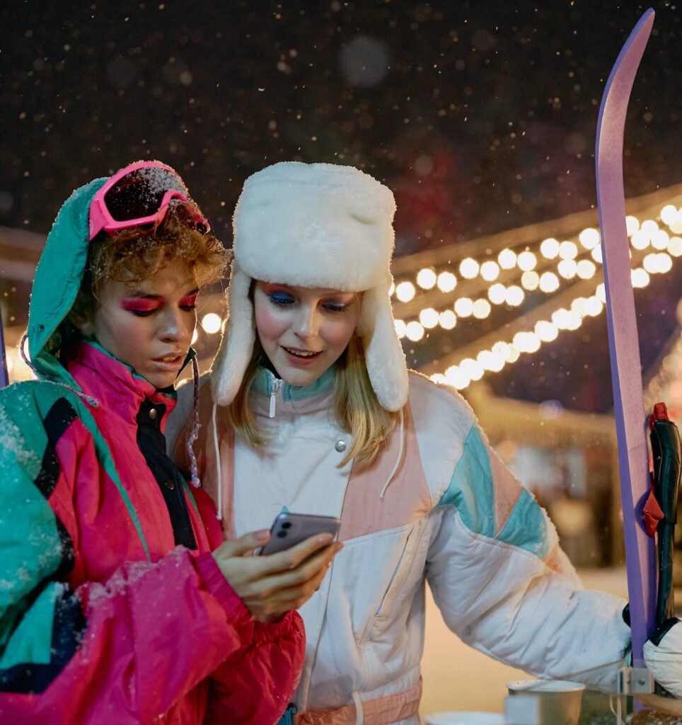 Women in Ski Suits Looking at a Smartphone